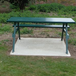 A frame picnic table vandal resistant with one side wheelchair access in green in a park for schools or inclusive seating arrangements