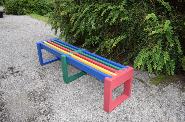 multicoloured backless straight bench on gravel beside tree